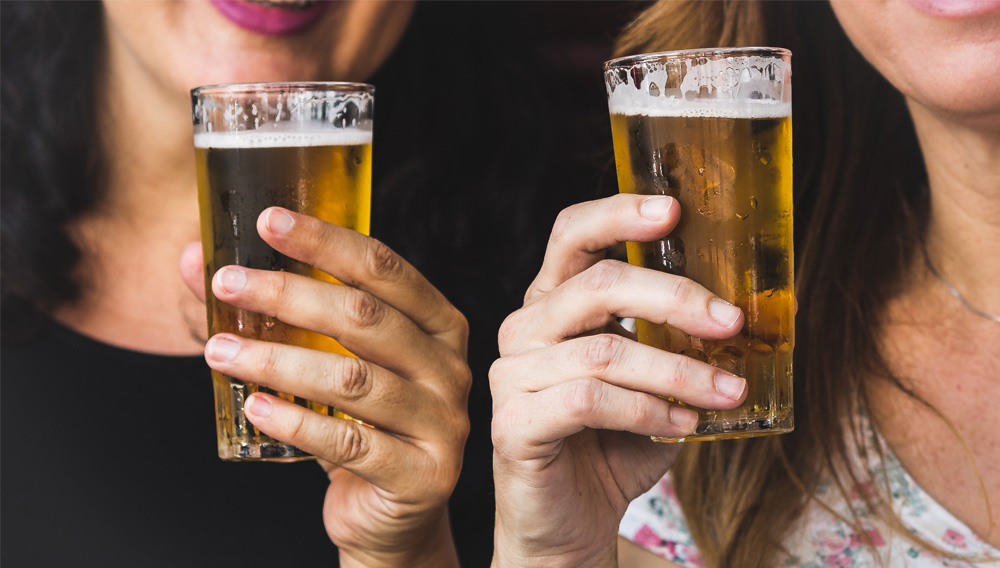 Two women holding beer glasses (Photo: Paloma A. on Unsplash)
