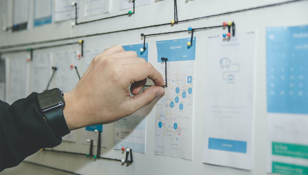 Hand inserts drawing pin into a planning board (Photo: Alvaro Reyes on Unsplash)