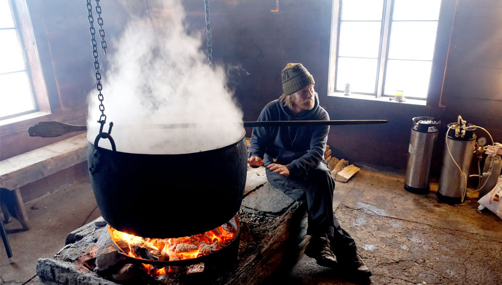 Dag Jørgensen warming himself by the kettle full of juniper infusion