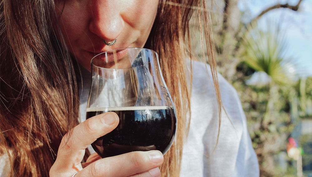 Woman testing the aroma of a dark beer (Photo: Monica di Loxley on Unsplash)