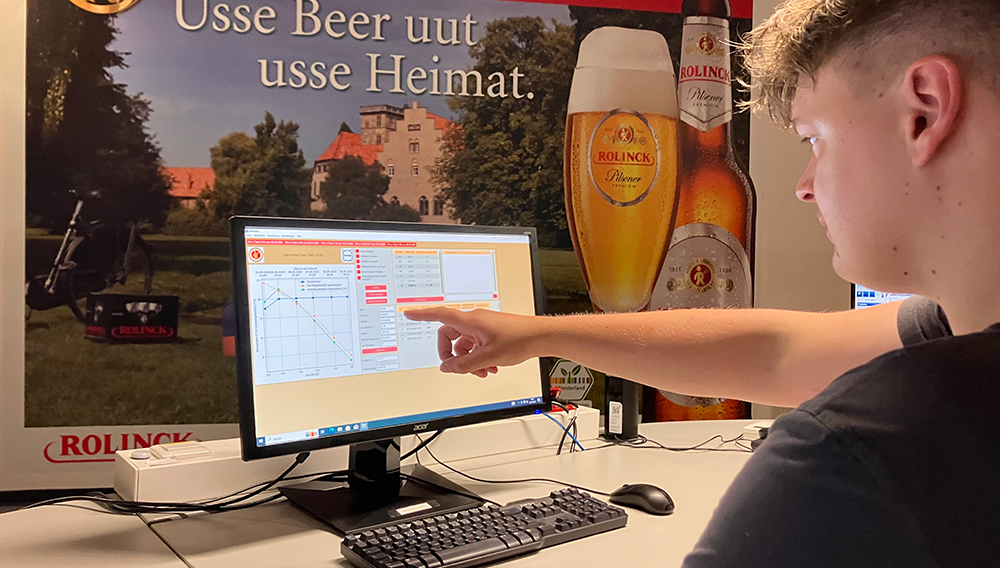 AI user pointing to status detail of the BrewTwin software, which can be seen on a monitor (Photo: Westfälische Hochschule)