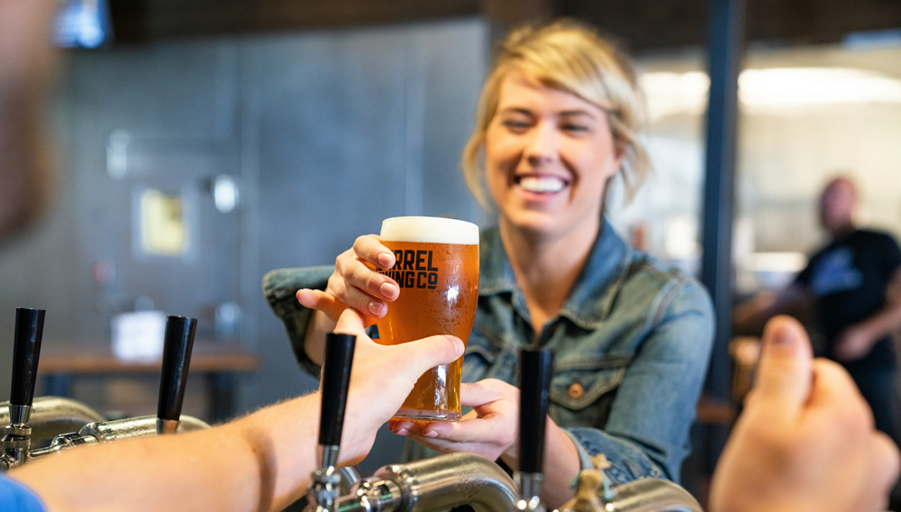 Person passing a glass of beer over a bar counter (Elevate on Unsplash)