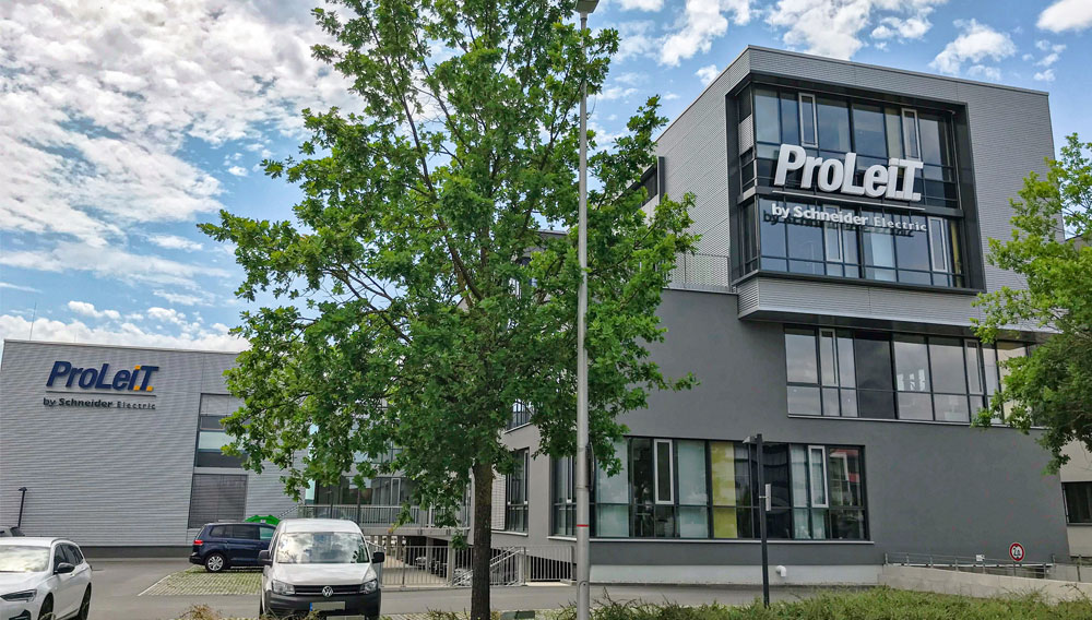 Outside view of a large grey company building bearing a logo saying, ProLeit by Schneider Electric