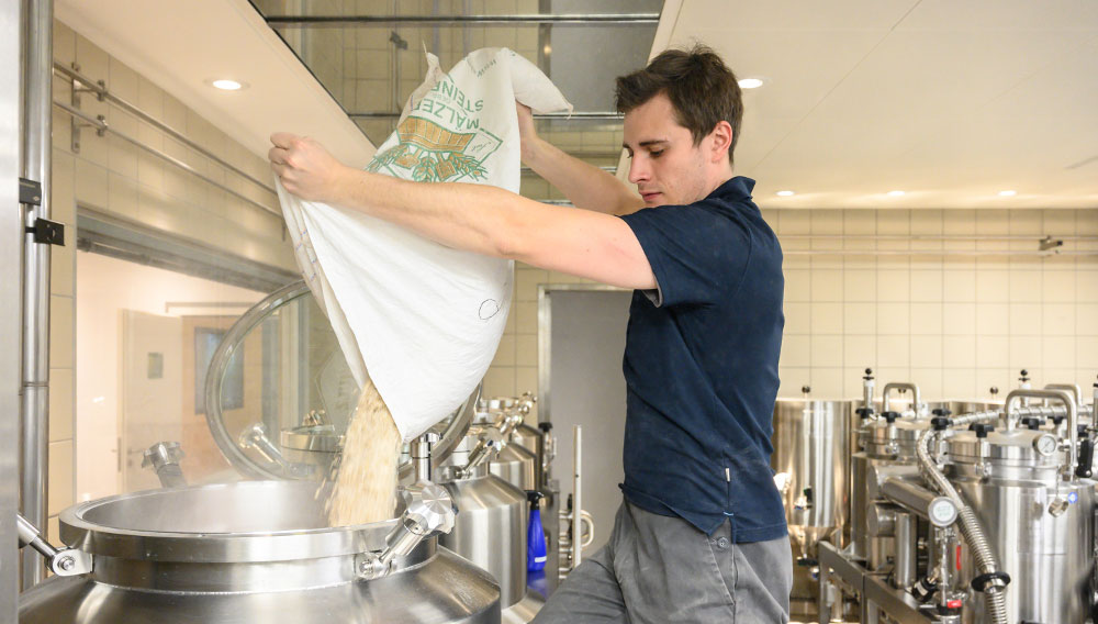 Brewer tipping hop pellets into a brewing kettle (Photo: BarthHaas)