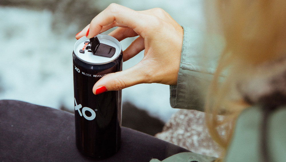 One hand operates the resealable mechanism of a beverage can