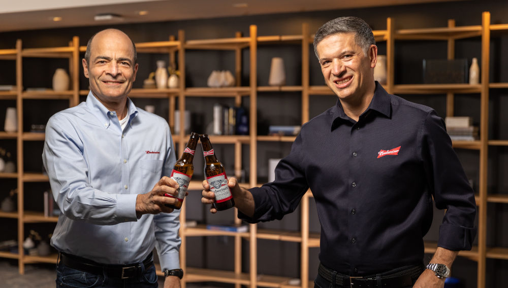 Michel Doukeris (right) and Carlos Brito toast with two bottles of beer