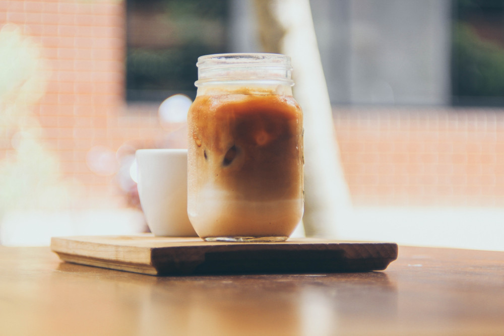 Glass jar with cold brew coffee on wooden coaster (Photo by Luis Reyes on Unsplash)