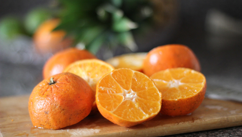Sliced orange fruit on wooden tray (Photo by J. Kelly Brito on Unsplash)
