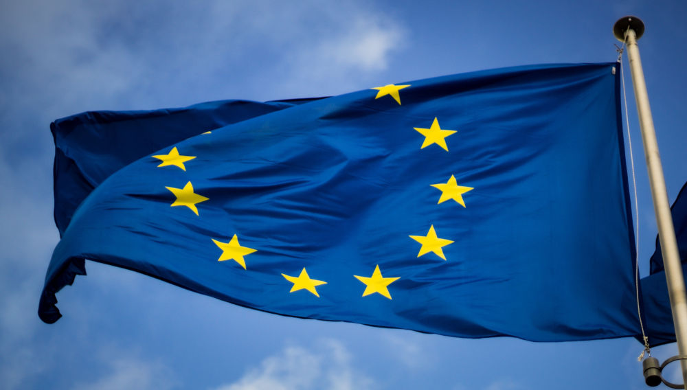 European Union Flag against blue sky (Photo by Christian Lue on Unsplash)
