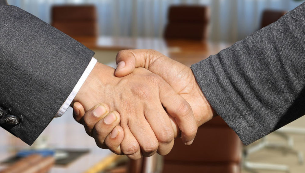 Two people in business suits shaking hands, close-up (Photo: Gerd Altmann on Pixabay)