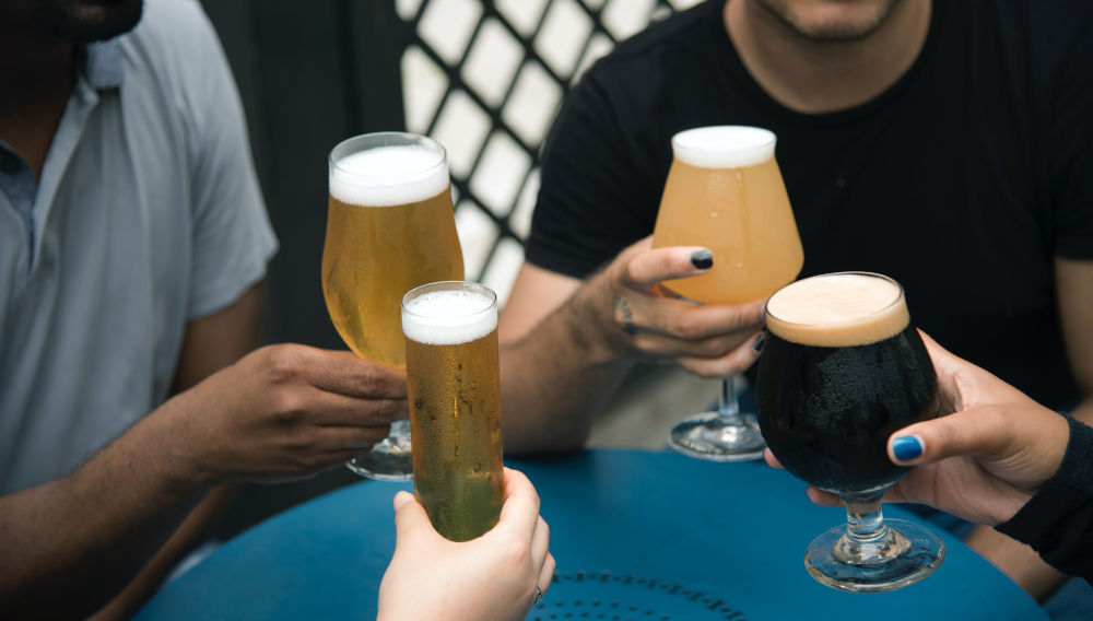 Four hands holding beer glasses (Photo: Elevate on Unsplash)