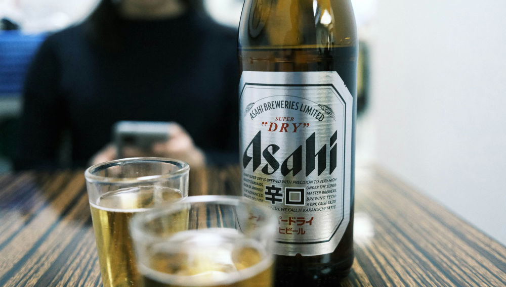 Asahi Super Dry bottle and two glasses, close-up (Beaumont Yun on Unsplash)