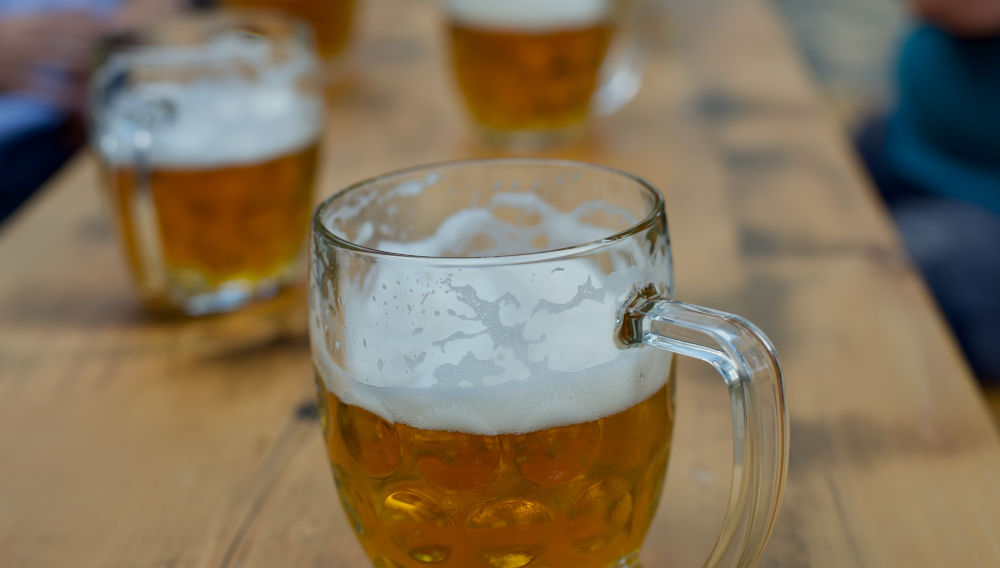 Glass beer mugs on a table (Photo: Bohdan Stocek on Unsplash)