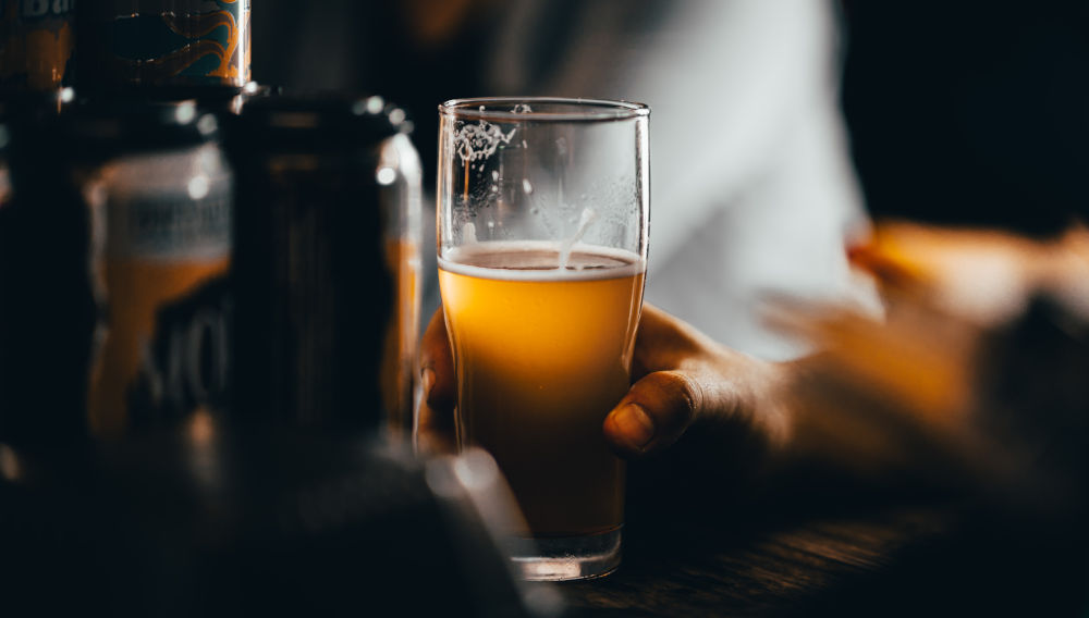 Hand holding a glass of beer (Source: Josh Olalde on Unsplash)