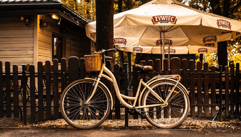 Weißes Retro-Fahrrad lehnt an einem Biergartenzaun (Foto von Omar KH auf Unsplash)