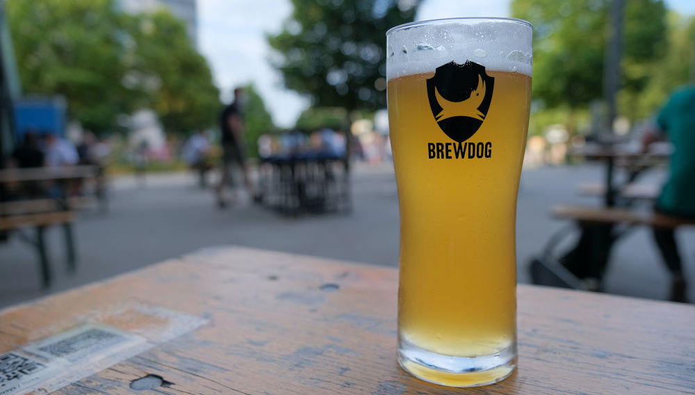 Clear Brewdog beer glass containing a light-coloured beer, on a table (Photo by Sebastian Herrmann on Unsplash)