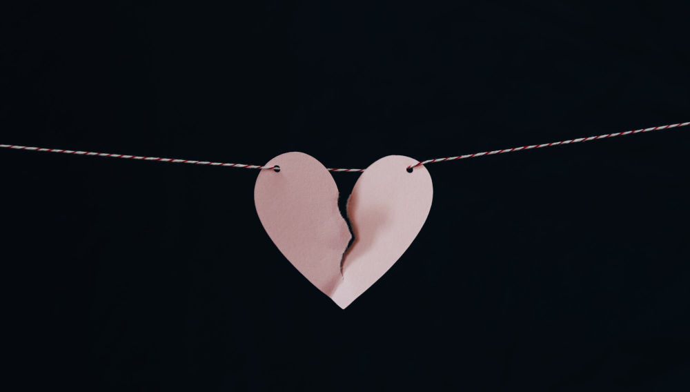 Torn red paper heart on a clothesline (Photo by Kelly Sikkema on Unsplash)