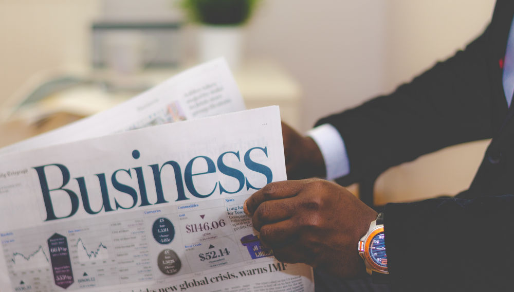 Businessman opening a newspaper (Photo by Adeolu Eletu on Unsplash)