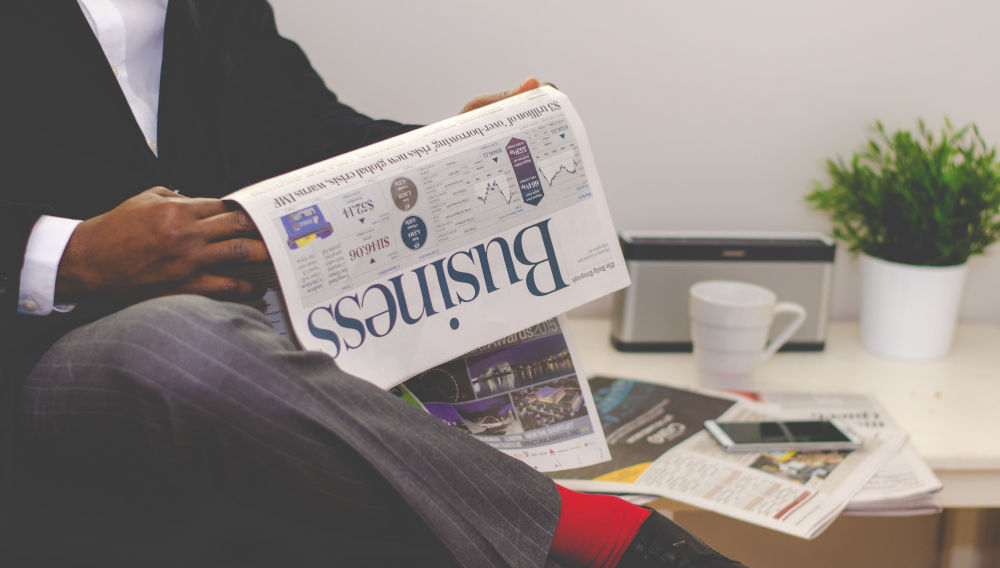 Person wearing a suit and holding a business paper (Photo by Adeolu Eletu on Unsplash)