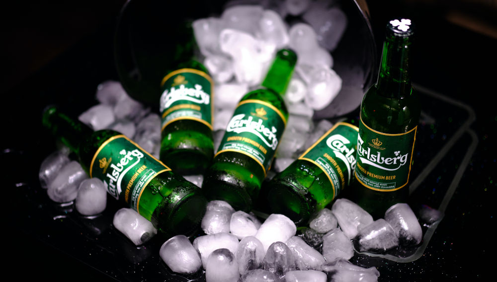 Green Carlsberg bottles on crushed ice (Photo: Himanshu Choudhary on Unsplash)