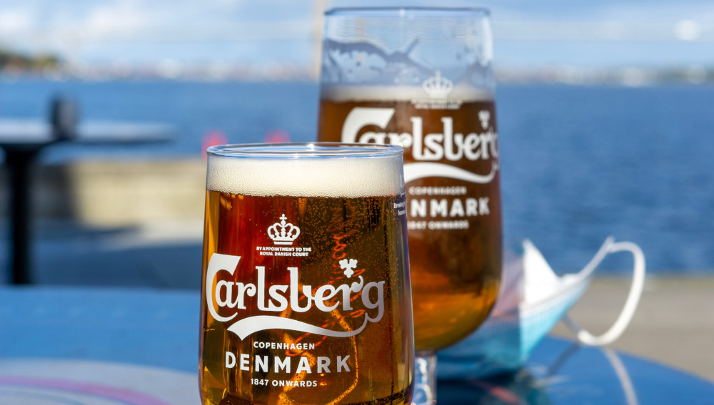 Two Carlsberg glasses containing a beer-like beverage (Photo: Elin Tabitha on Unsplash)