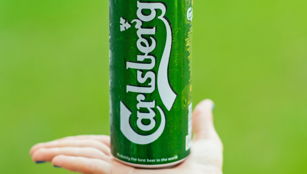Green Carlsberg can on the palm of a hand (Photo by Engin Akyurt on Unsplash)