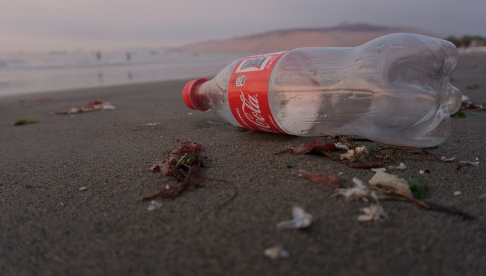 Coca-Cola bottle on the beach (Photo: Maria Mendiola on Unsplash)