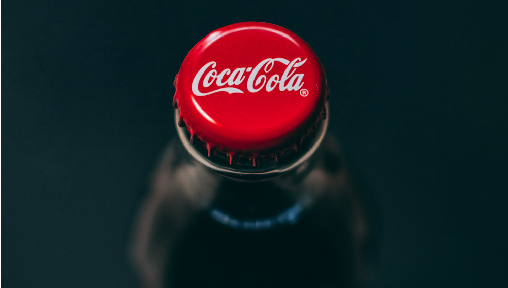 Red Coca Cola cap on a brown bottle (Photo by Taras Chernus on Unsplash)