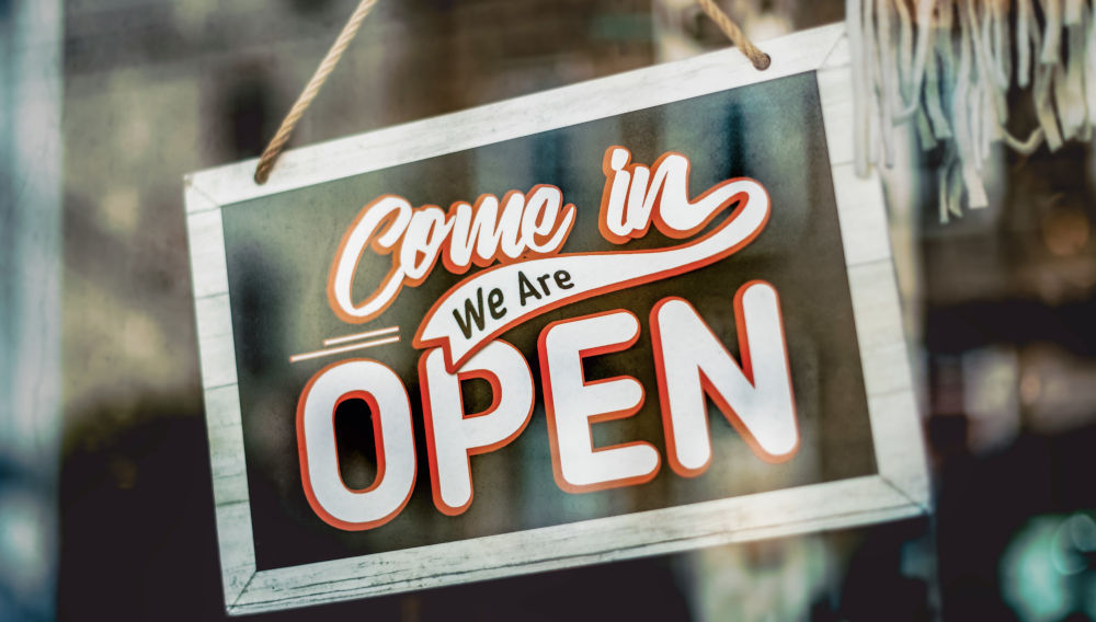 Sign in a window, saying, ‘Come in we're open’ (Photo: Tim Mossholder on Unsplash)