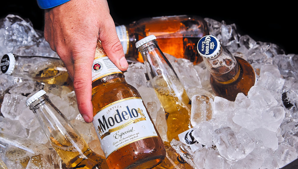 Person grapping a Modelo bottle from a cooler filled with ice (Photo by James Kern on Unsplash)