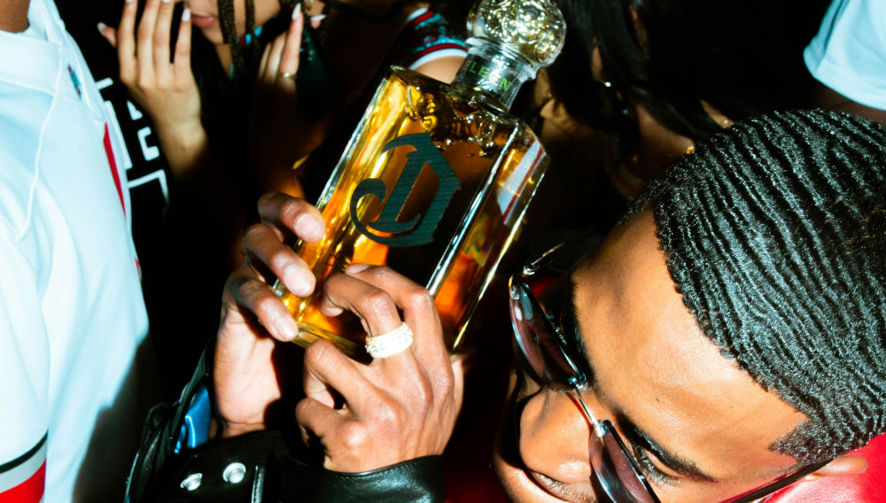 man at a party holding a bottle of DeLeon Tequila (Photo: Strvnge films on Unsplash)