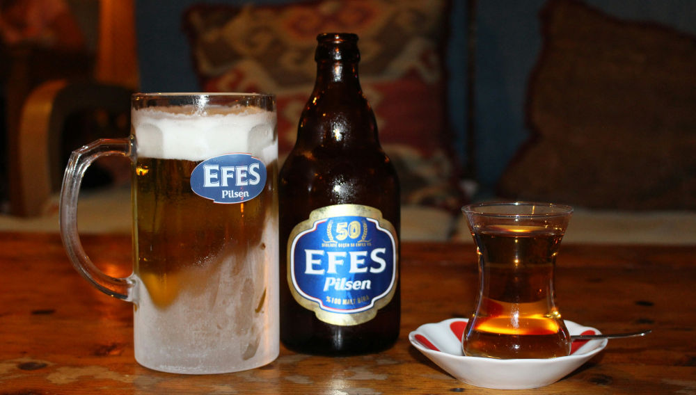 Efes beer glass and bottle next to a Turkish tea glass (Photo:  Jess May Russell on Unsplash)