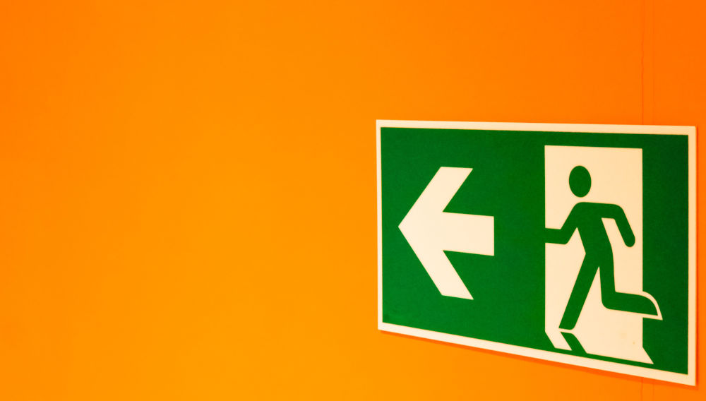 Exit sign in front of orange background (photo: ddp/Unsplash)