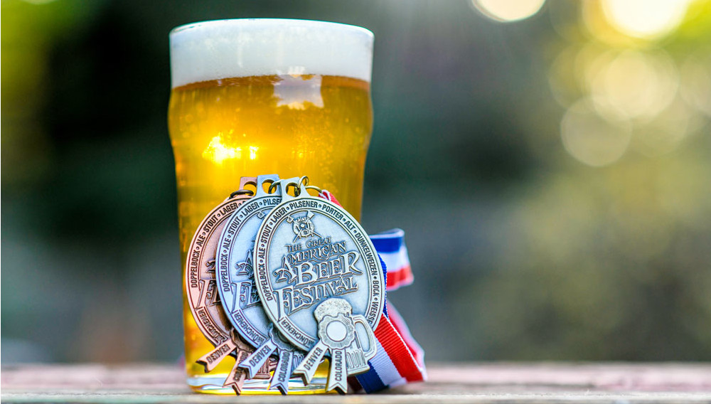 Medals of the Great American Beer Festival leaning on a glass of beer (Photo: Brewers Assocciation)