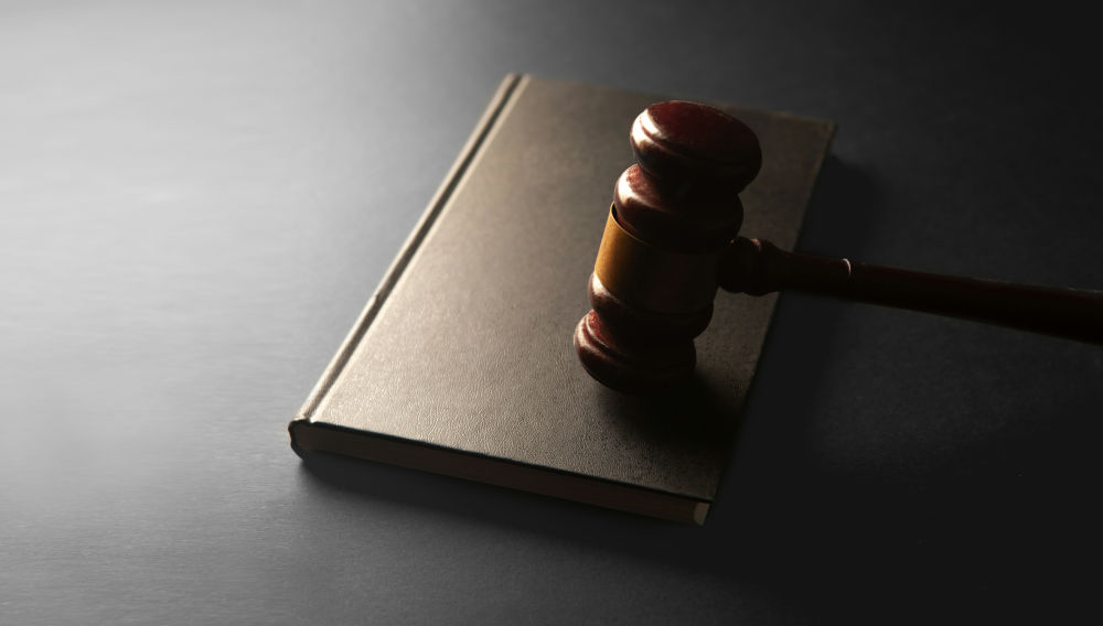 Wooden gavel on a brown book, on a black surface (Photo: Sasun Bughdaryan on Unsplash)