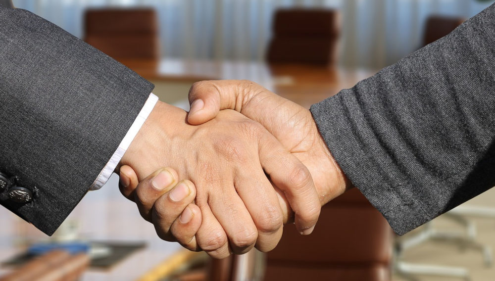 Two people in business suits shaking hands, detail (Photo by Gerd Altmann on Pixabay)