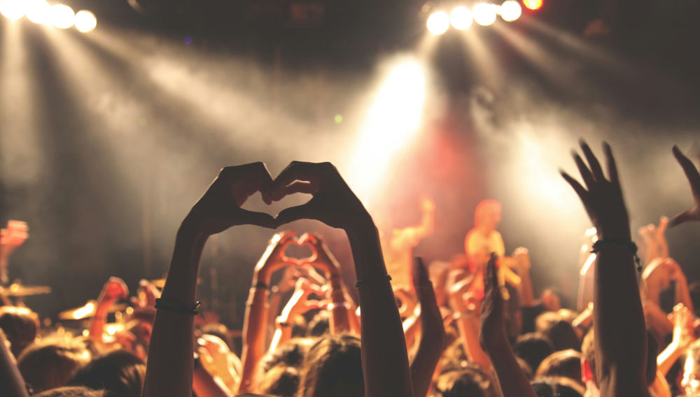 Menschen formen bei einem Konzert mit ihren Händen Herzen (Foto: Anthony DELANOIX auf Unsplash)