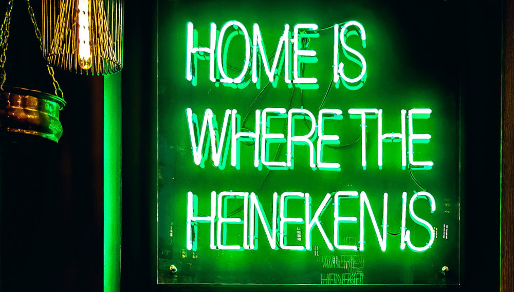 Green neon sign saying, “Home is where the Heineken is” (Photo by John Rodenn Castillo on Unsplash)