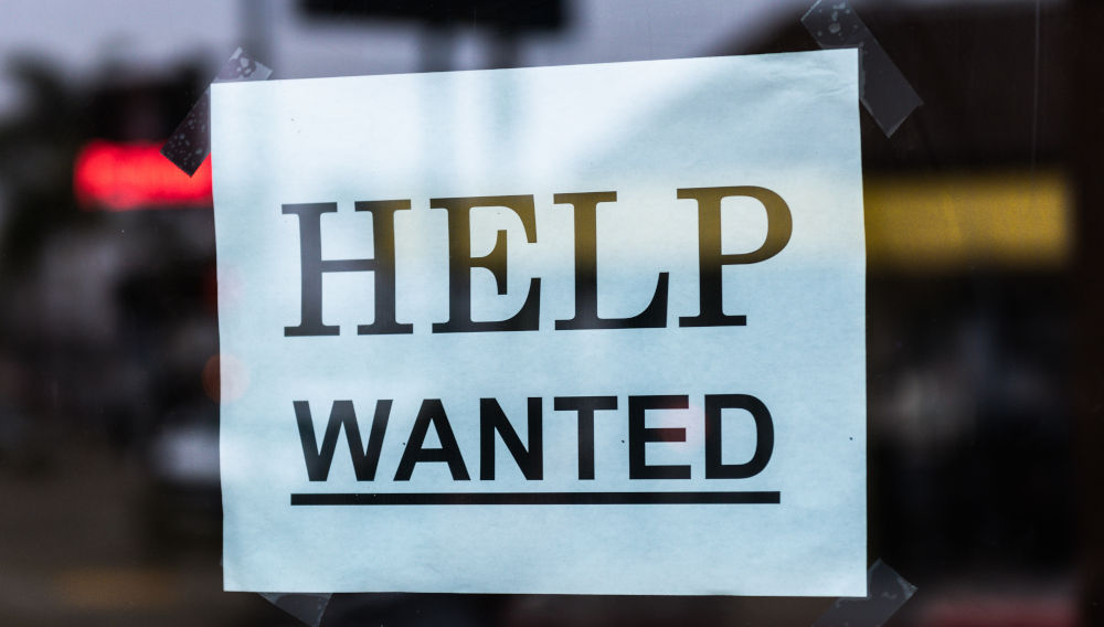 Black-and-white window sign saying “Help wanted” (Photo by Tim Mossholder on Unsplash)