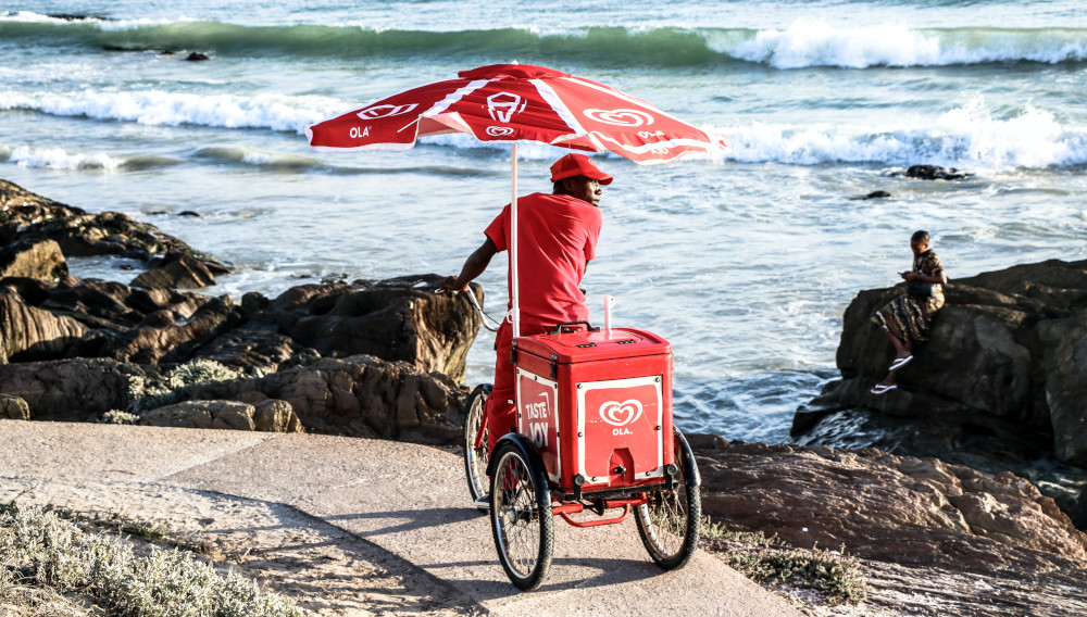 A man selling icecream with an bike on a beach near Cape Town in South Africa (Photo: Louis Smit, Unsplash)