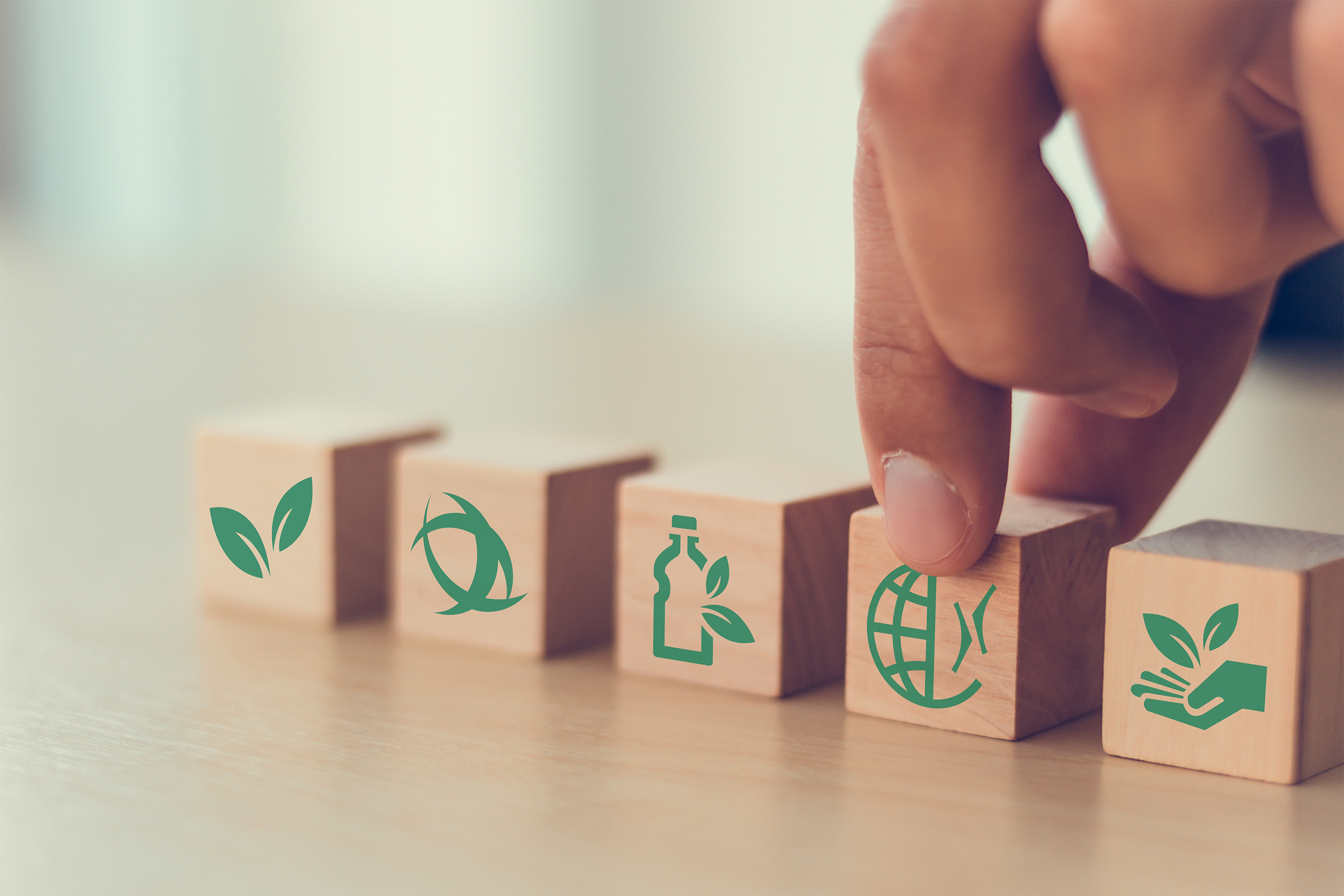 Hand holding building blocks with different sustainability symbols