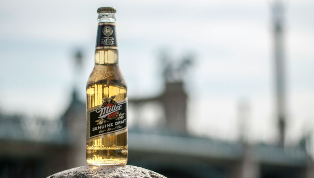 Bottle of Miler beer on a stone, against a blurry background (Photo: Csaba Talaber on Unsplash)