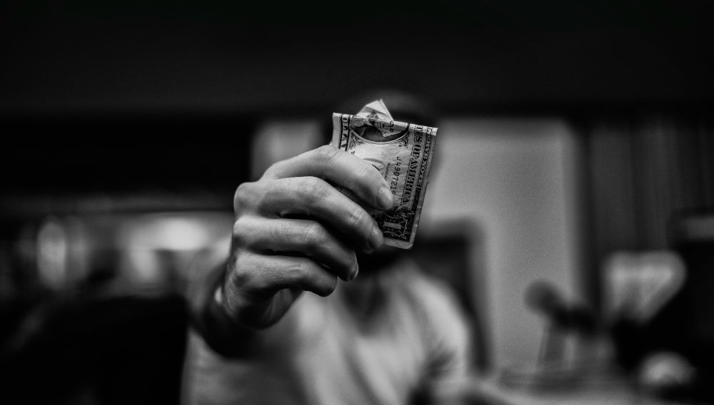 a man's hand with money (photo by Lucas Favre on Unsplash)