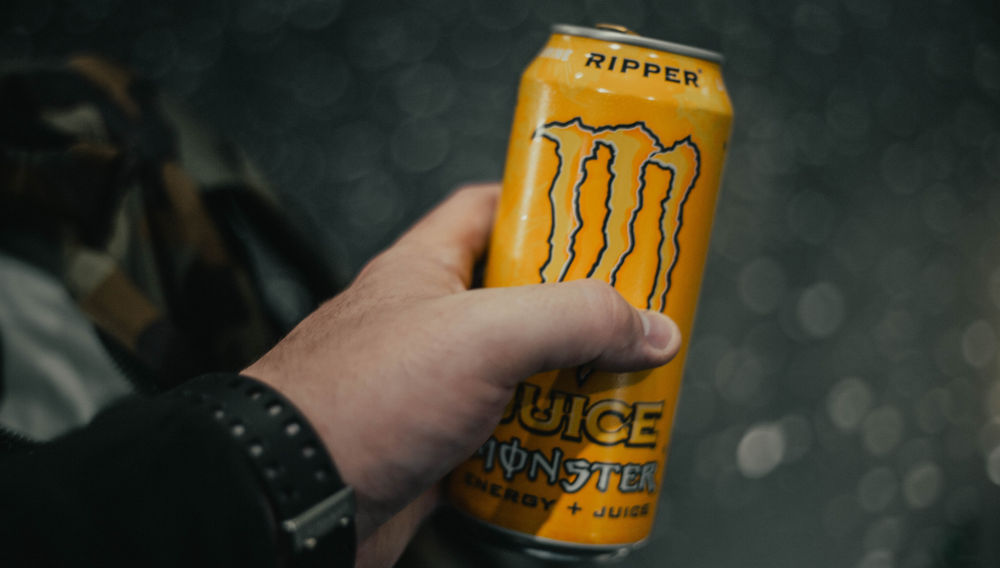 Hand holding yellow Monster can (Photo by Jonathan Cooper on Unsplash)