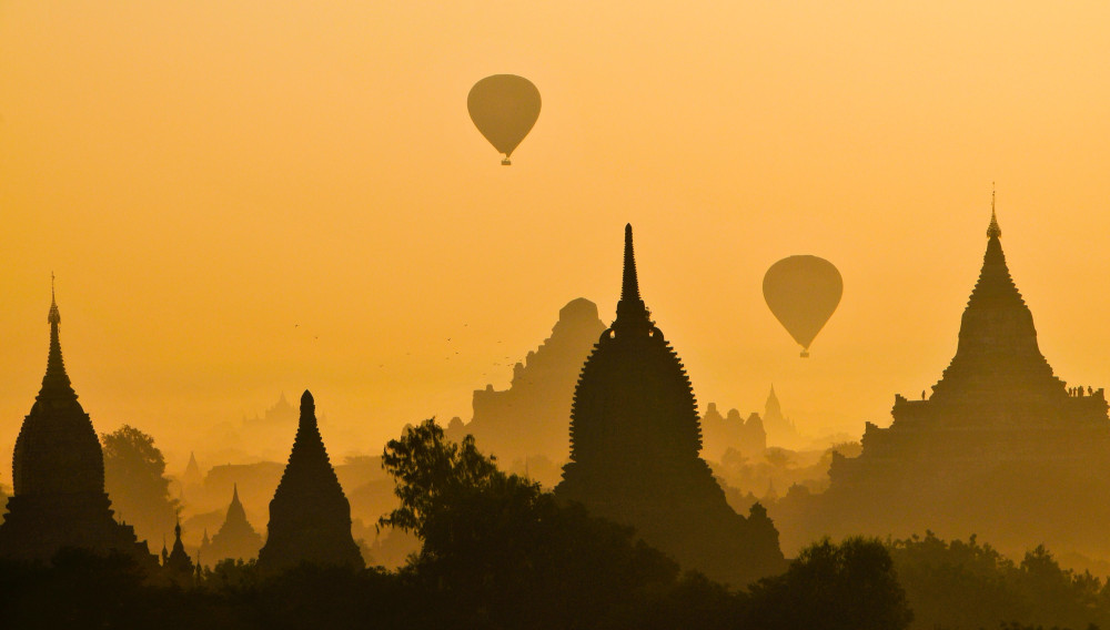 Bagan, Myanmar: Tempelsilhouetten vor orangefarbenem Himmel (Foto von Charlie Costello auf Unsplash)