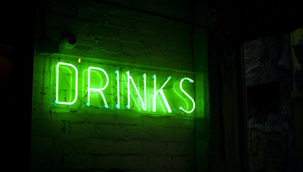 Neon green “drinks” sign (Photo by Stephan Valentin on Unsplash)