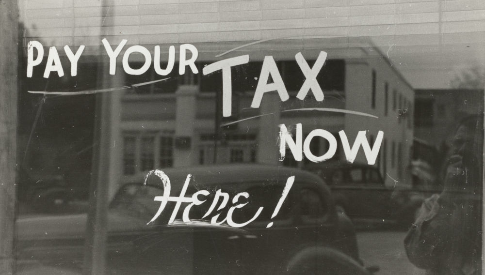 Lettering on window pane: Pay your tax (Photo by The New York Public Library on Unsplash)