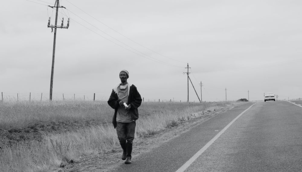 Person in black jacket walking down the road (Photo by Hennie Stander on Unsplash)