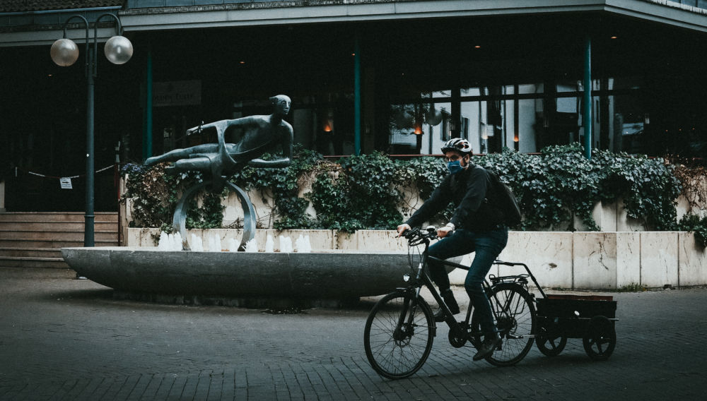 Person with face mask on a bike (Photo by Bennett Tobias on Unsplash)