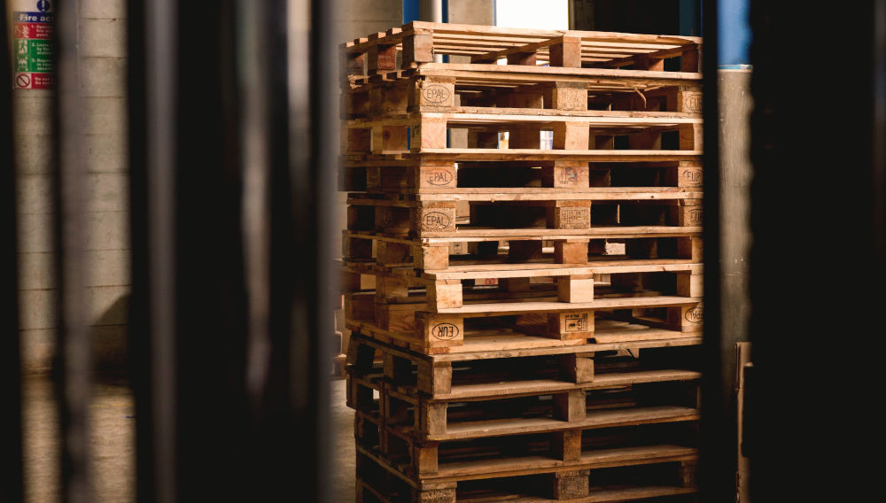 Piled wooden pallets (Photo by Reproductive Health Supplies Coalition on Unsplash)